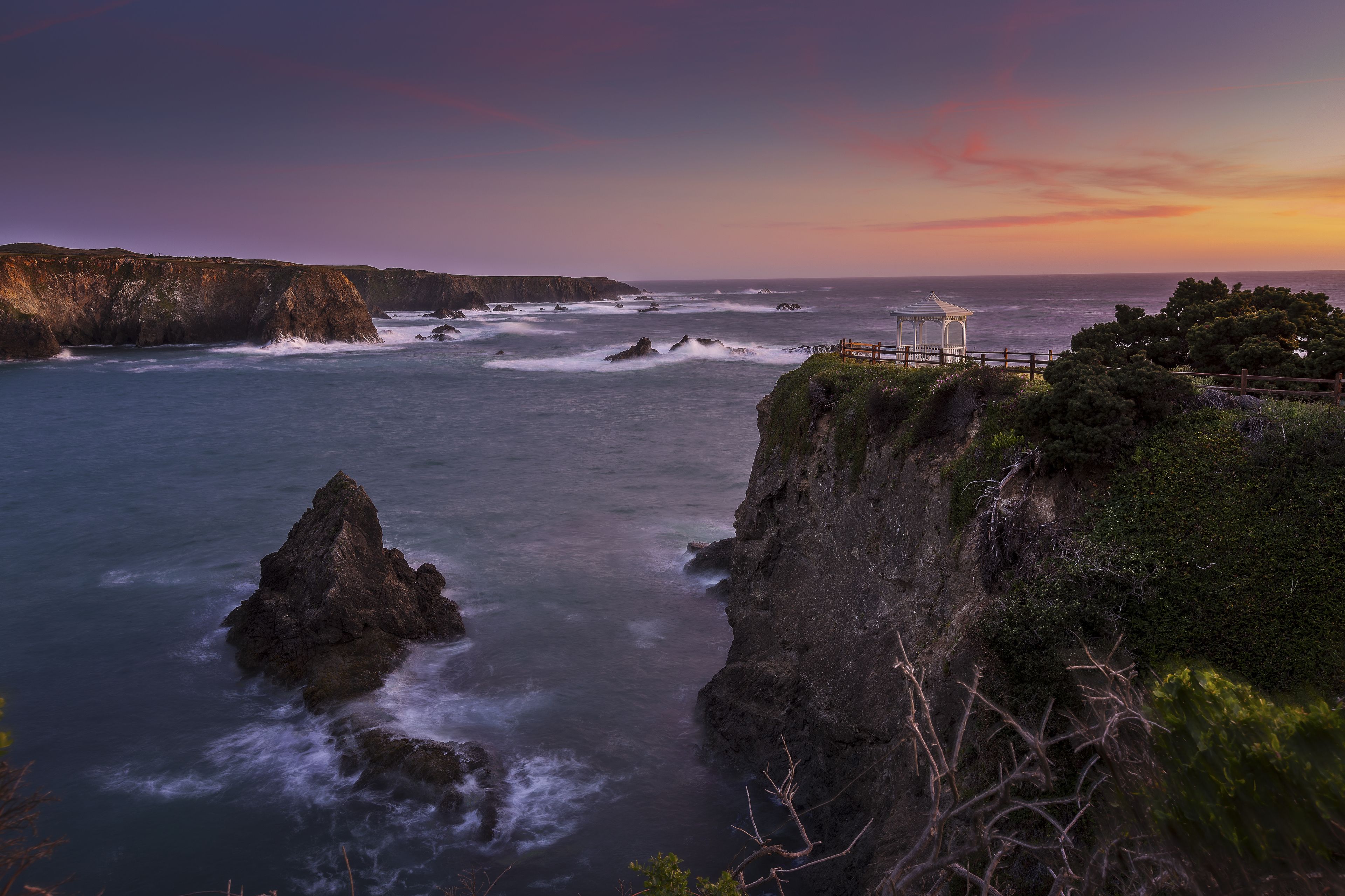 A coastal landscape with cliffs, waves, and a gazebo.