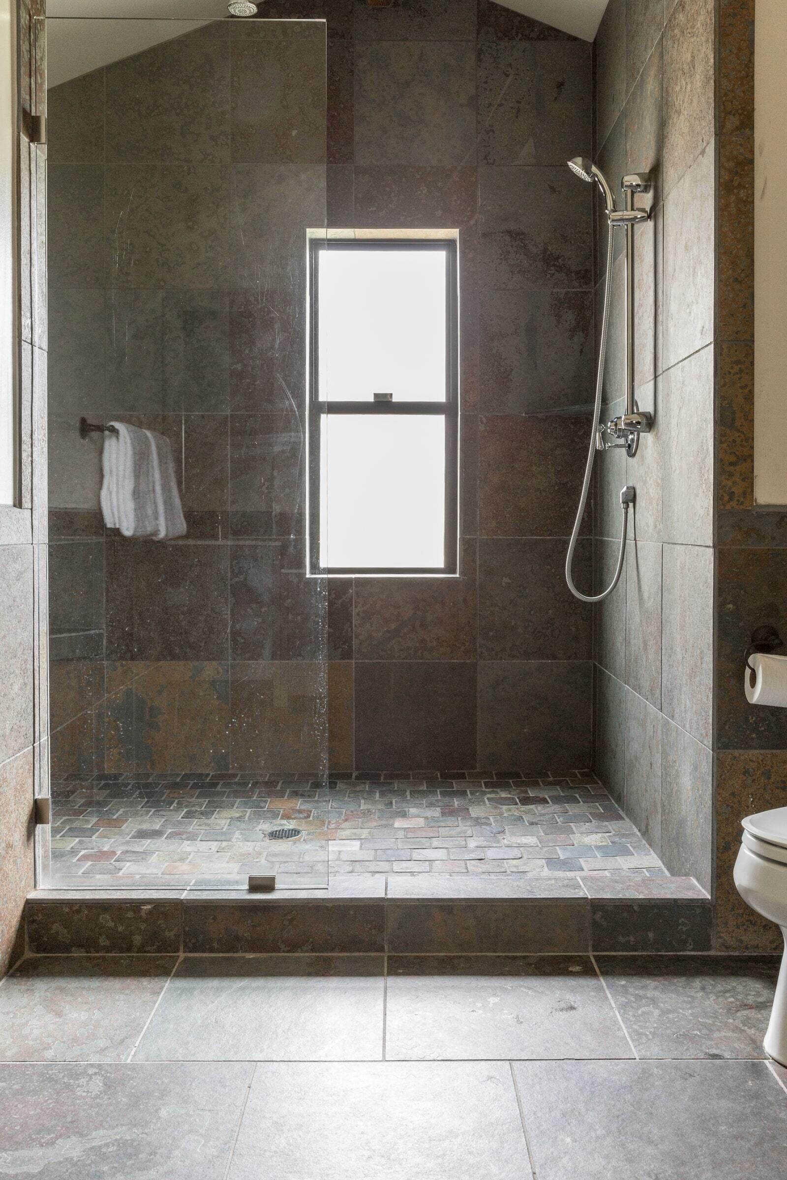 A shower area with a glass door, a towel rack, and a toilet.