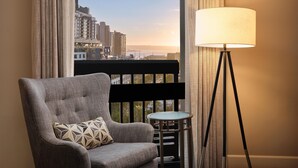 A room with a view of a cityscape, a chair with a patterned cushion, and a floor lamp. - The DEXTRO Little Italy, BW Premier Collection (San Diego)