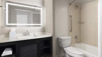 Un baño moderno con un espejo grande, un lavabo, un inodoro y una bañera.