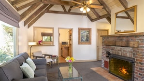 A living room with a fireplace, a sofa, a coffee table, and a ceiling fan. - The Pierpont Inn (Ventura)