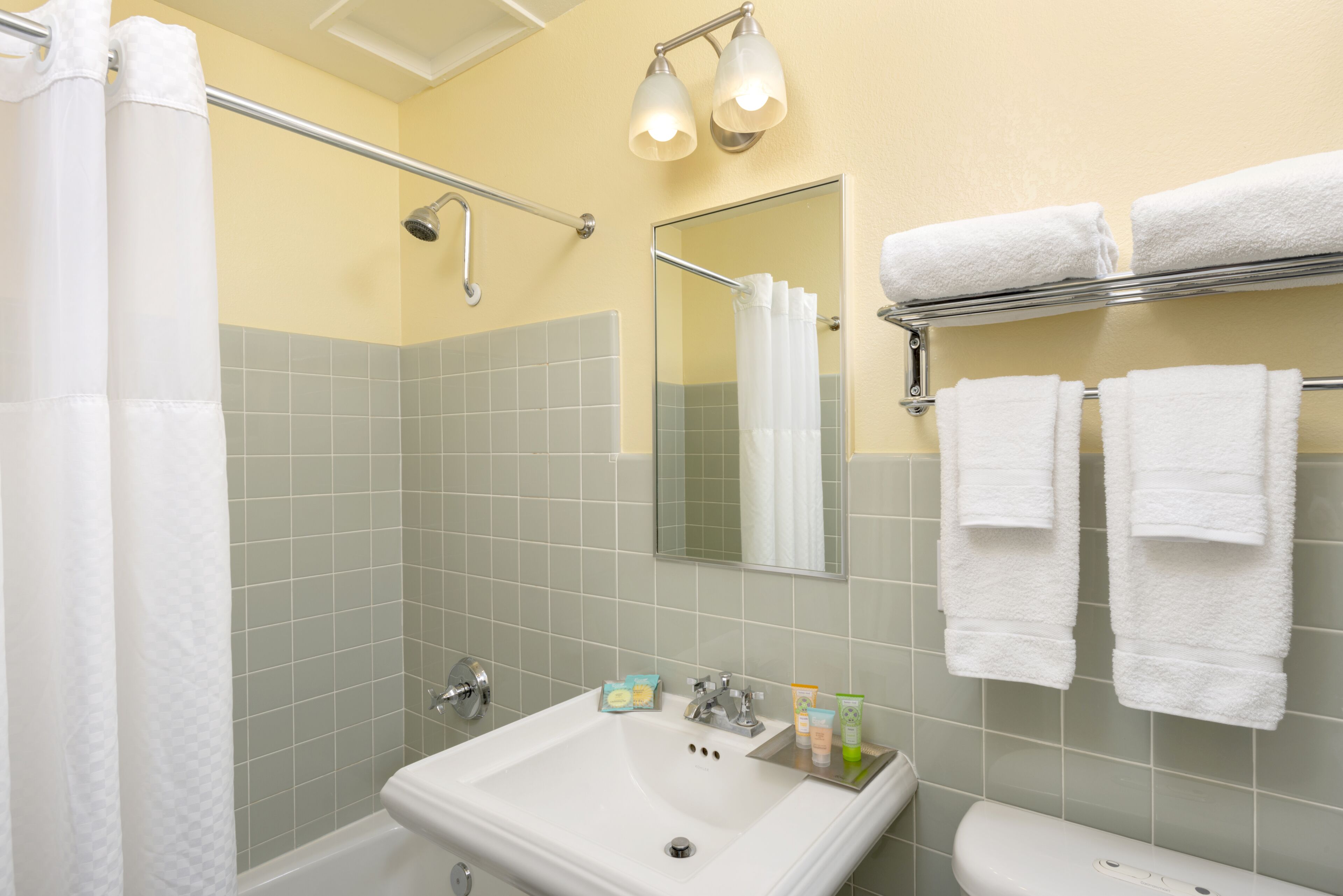 A bathroom with a sink, mirror, and two towel racks.