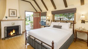 A bedroom with a fireplace, a bed, and a ceiling fan. - The Pierpont Inn (Ventura)