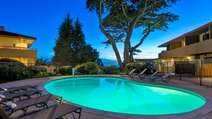 A swimming pool with lounge chairs and a large tree in the background. - The Pierpont Inn (Ventura)