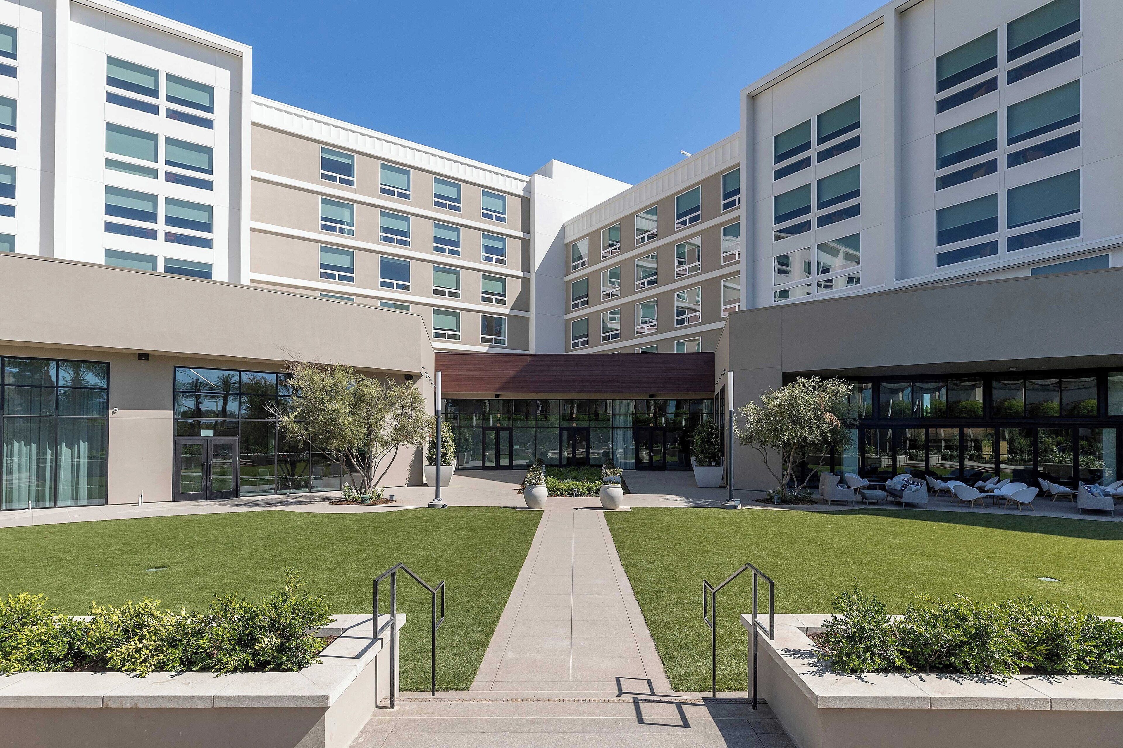A modern building with multiple floors, large windows, and a central courtyard with a pathway.