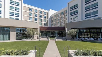 A modern building with multiple floors, large windows, and a central courtyard with a pathway.