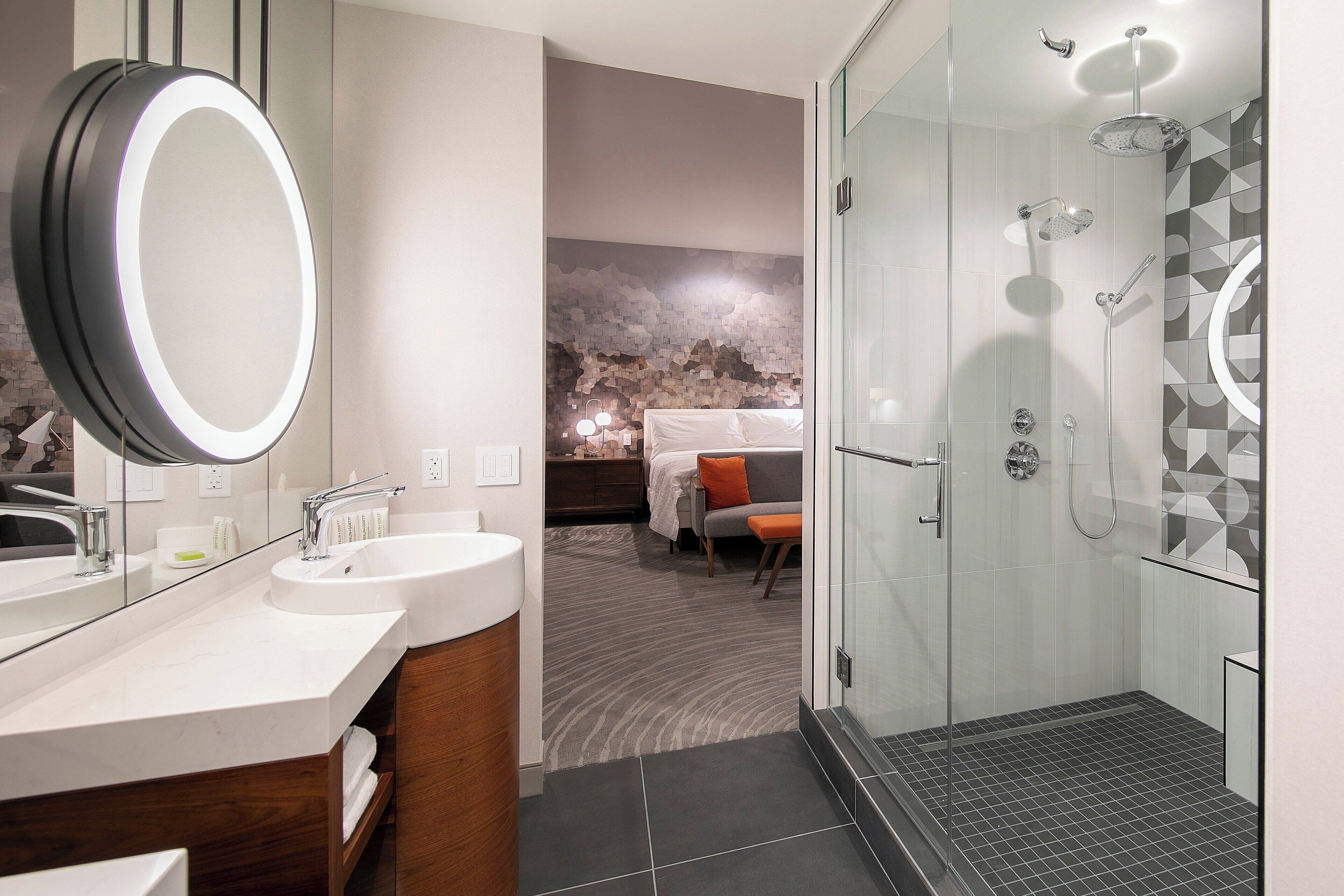 A modern bathroom with a large mirror, dual sinks, and a glass-enclosed shower.