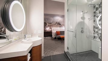 A modern bathroom with a large mirror, dual sinks, and a glass-enclosed shower.