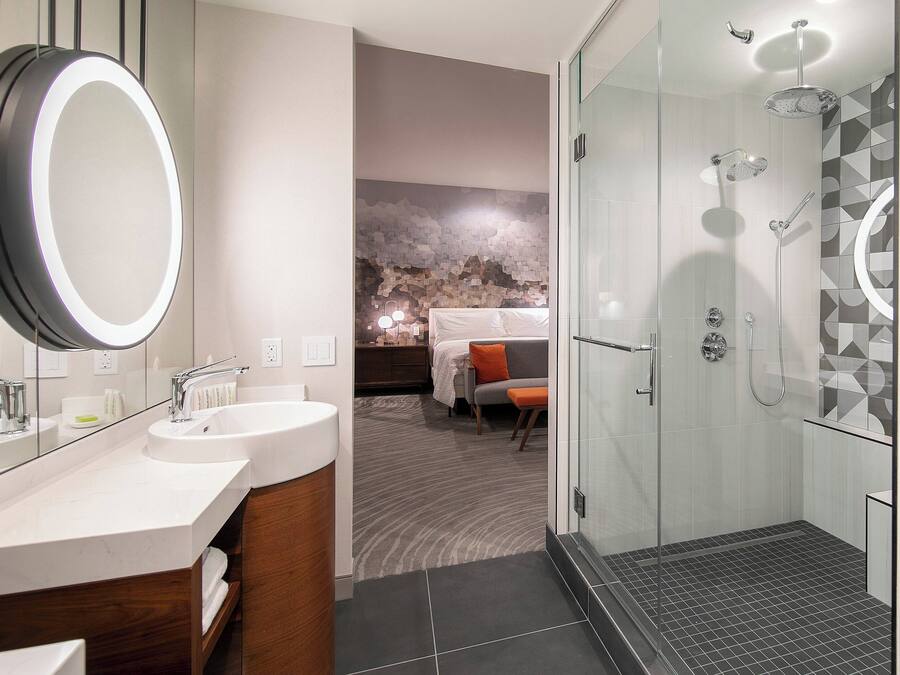A modern bathroom with a large mirror, dual sinks, and a glass-enclosed shower.