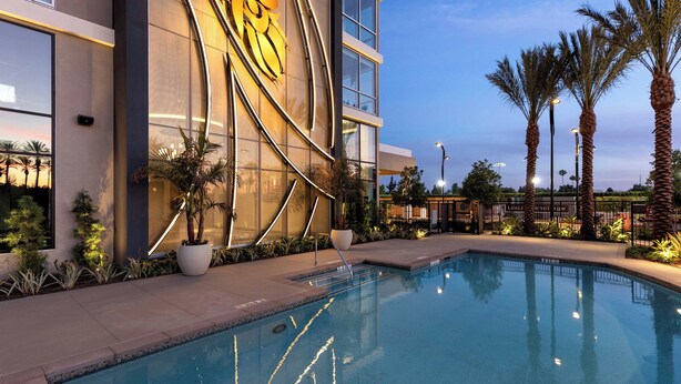 A modern hotel with a large pool, palm trees, and a distinctive golden design on the building facade. - Le Méridien Pasadena Arcadia (Arcadia)