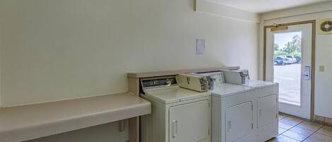 A laundry area with a washing machine, dryer, and a bench.
