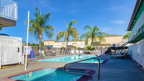 A pool area with two pools, palm trees, and a building in the background. - Motel 6 Fresno, CA - Yosemite Hwy (Fresno)