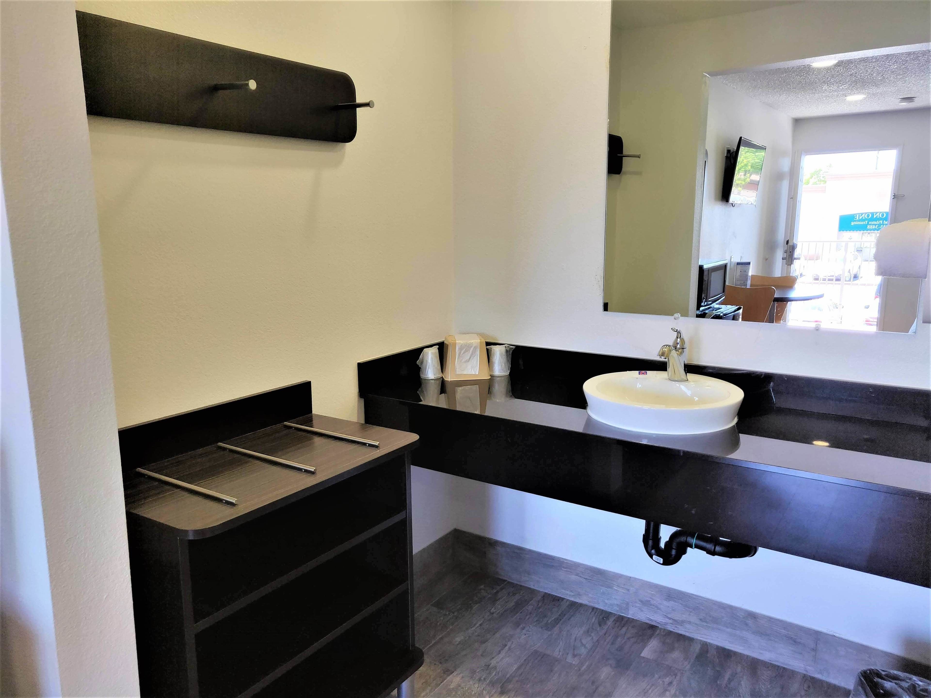 A modern bathroom with a black vanity, white sink, and a mirror above the sink.