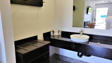 A modern bathroom with a black vanity, white sink, and a mirror above the sink.