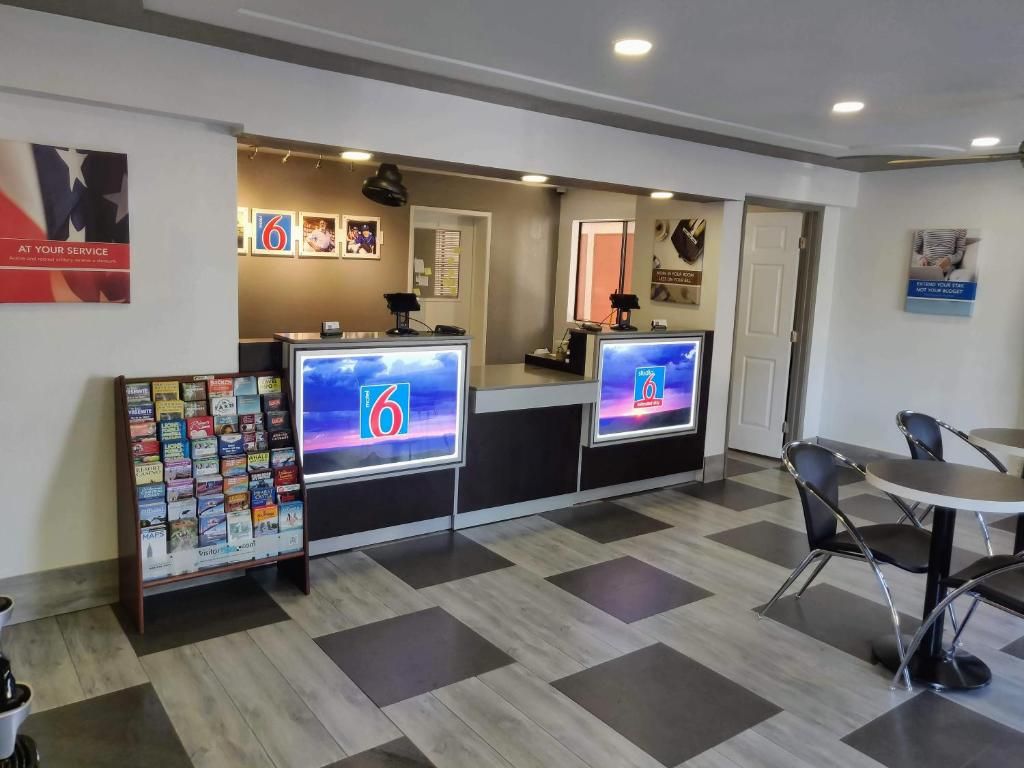 Un espace d’accueil comprenant un comptoir d’enregistrement, un panneau d’affichage et un coin salon.