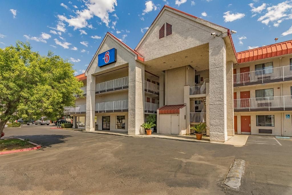 A motel with a '6' sign, multiple balconies, and a parking lot.
