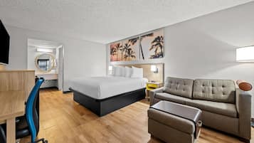 A modern hotel room with a bed, a sofa, a desk, and a chair.
