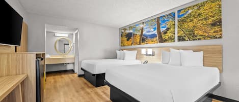 A hotel room with a large bed, two bedside tables, a TV, a mirror, and a wall with three paintings.