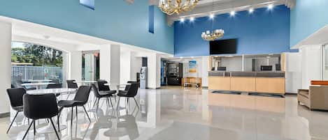 A spacious lobby with a modern design, featuring a large seating area, a kitchen area, and a television mounted on the wall.