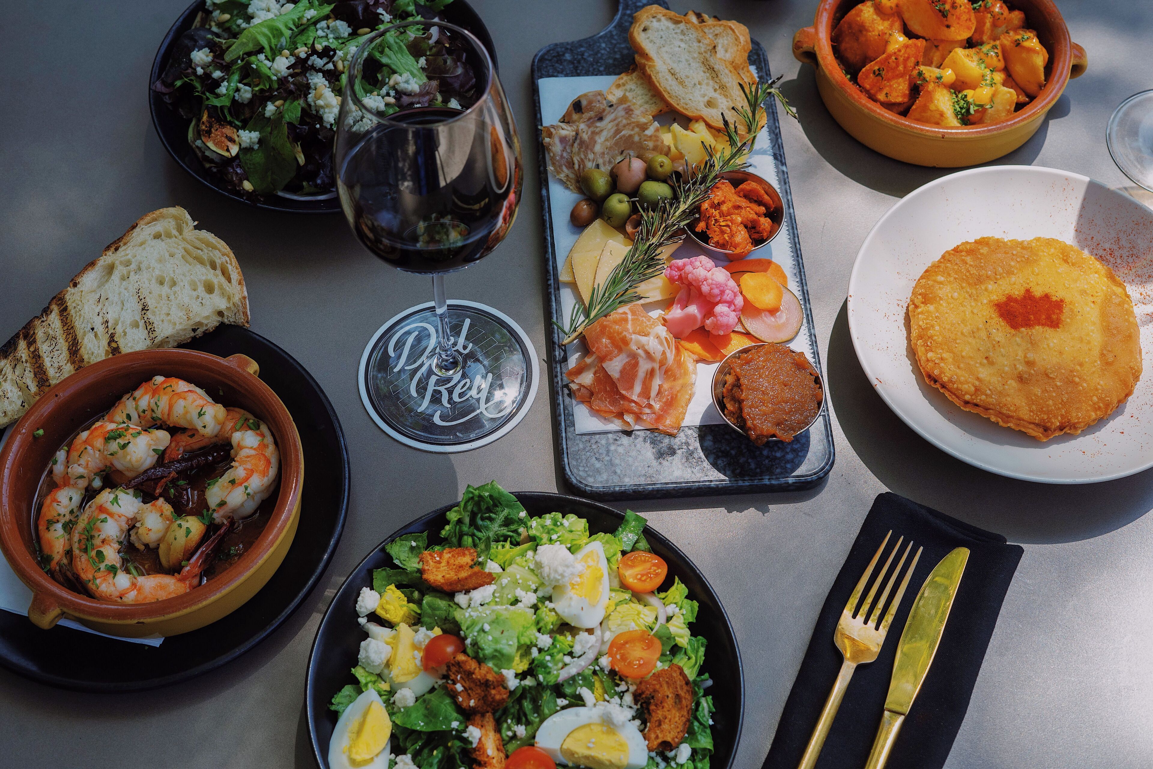 Une table dressée avec différents plats, notamment des crevettes, une salade et du pain.