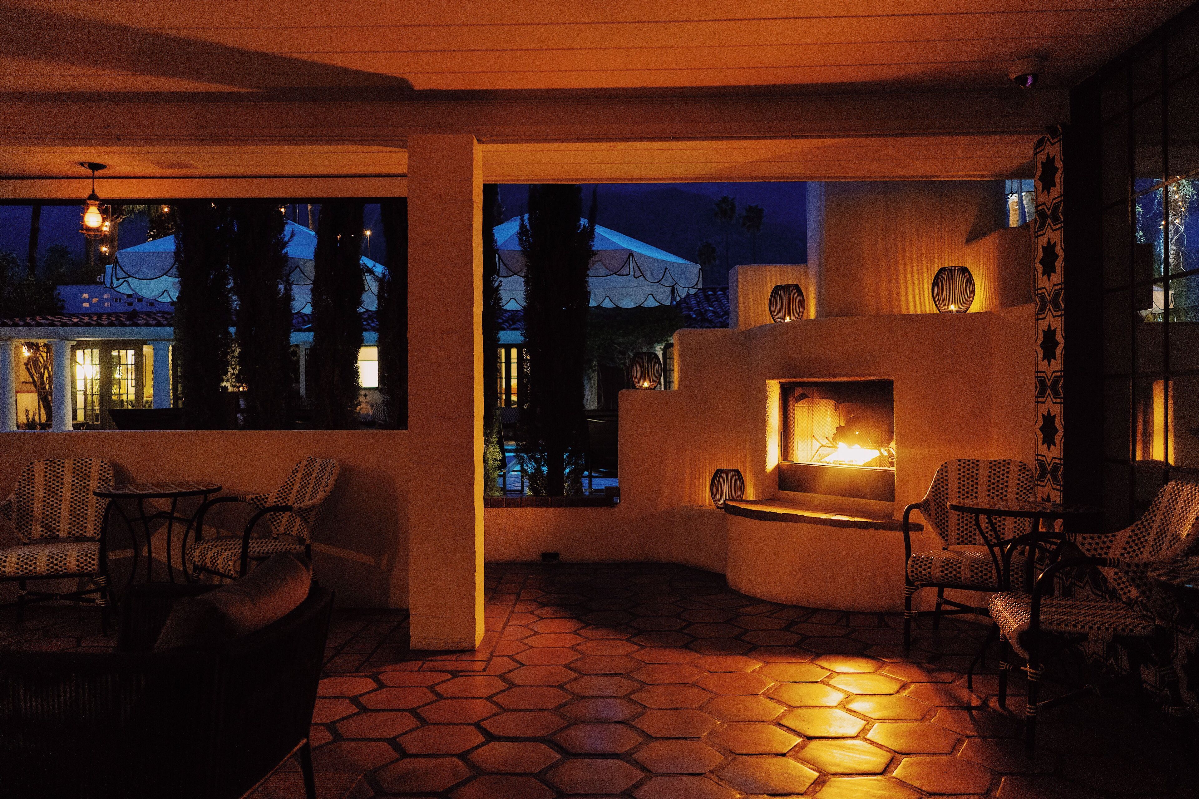 An outdoor patio area with hexagonal tiles, wicker furniture, and a fireplace.
