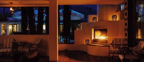 An outdoor patio area with hexagonal tiles, wicker furniture, and a fireplace.