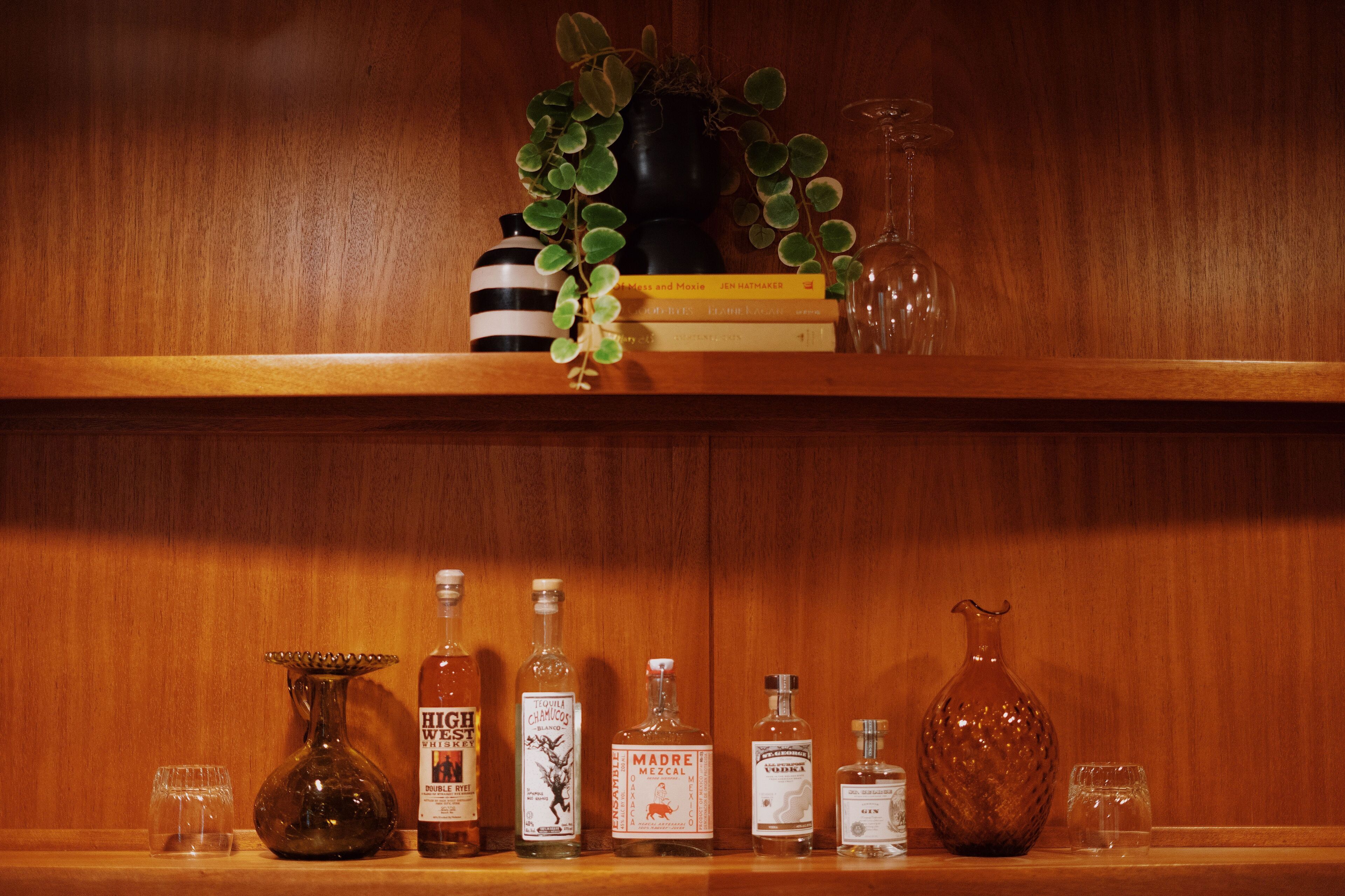 Une étagère en bois avec différentes bouteilles et un vase.