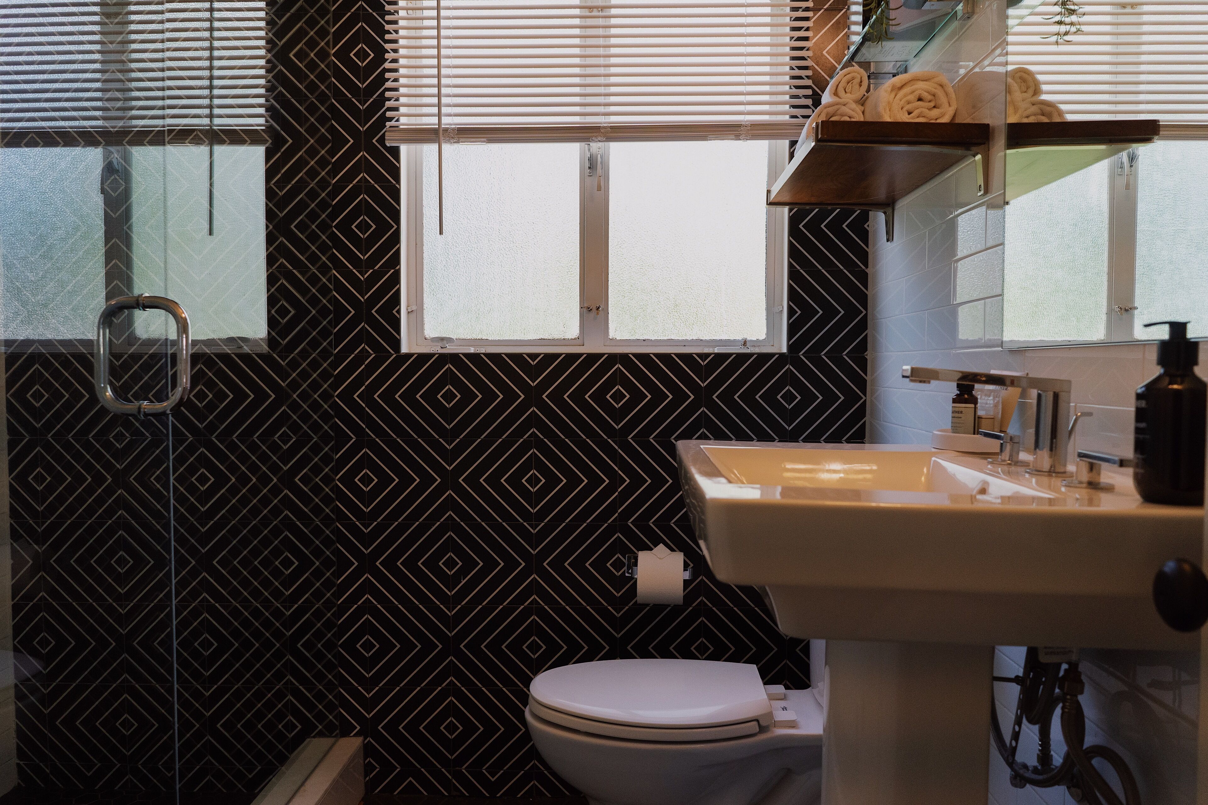 A bathroom with a toilet, sink, and window with blinds.