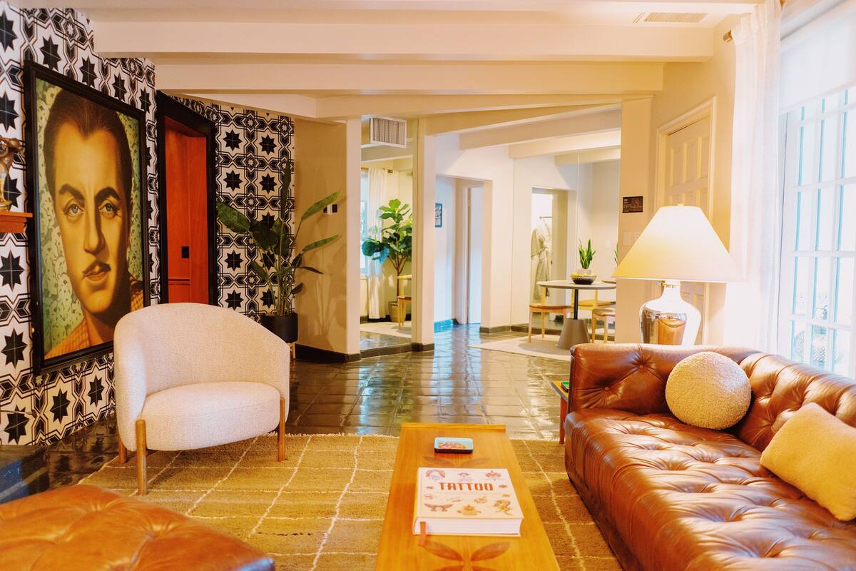 A spacious living room with a leather sofa, a coffee table, and a framed portrait on the wall.