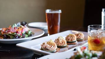 A dining table with a variety of dishes, including a salad, a plate of appetizers, and a glass of iced tea.