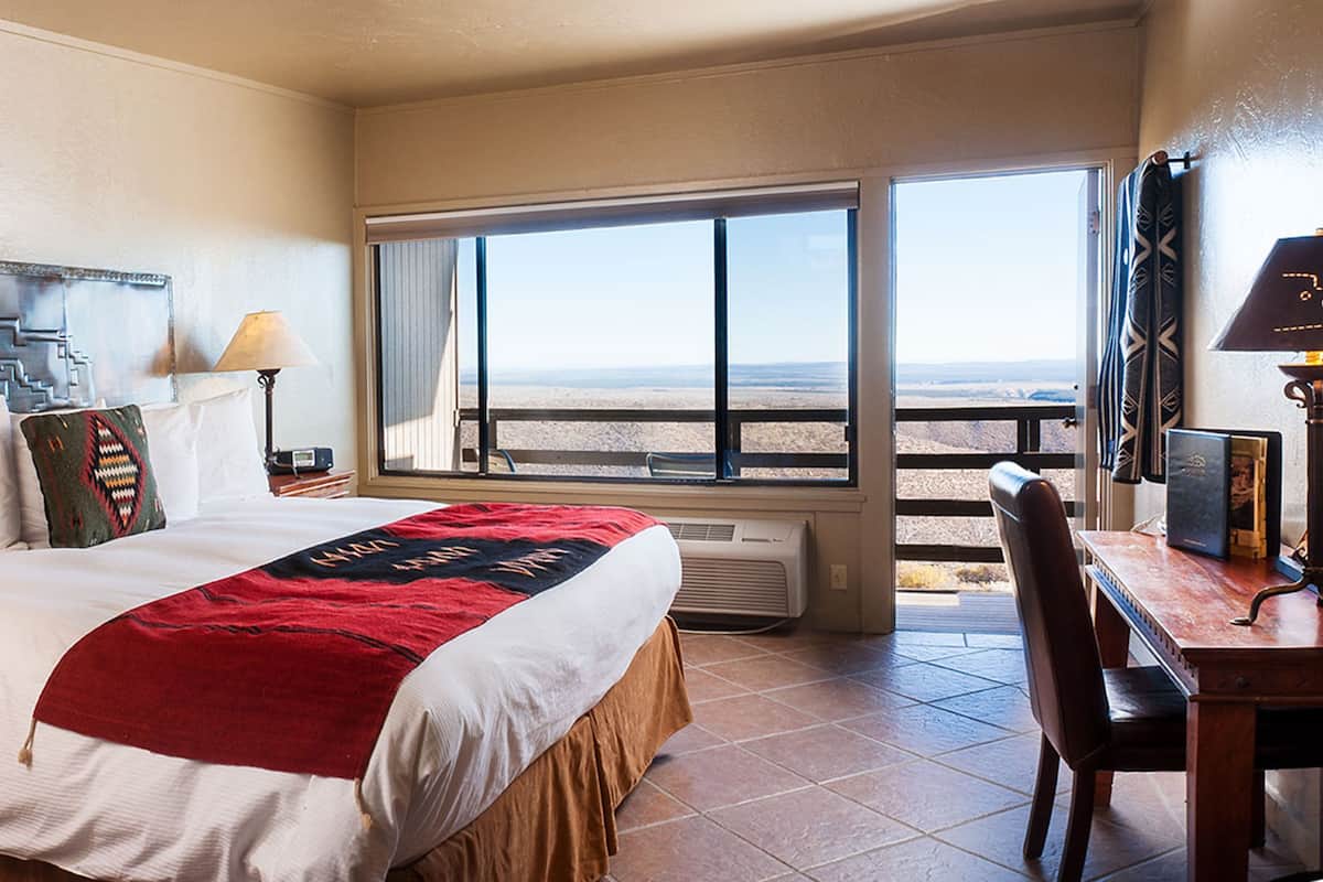 Habitación de hotel con cama, escritorio, silla, ventana y vistas al desierto, además de un calefactor.