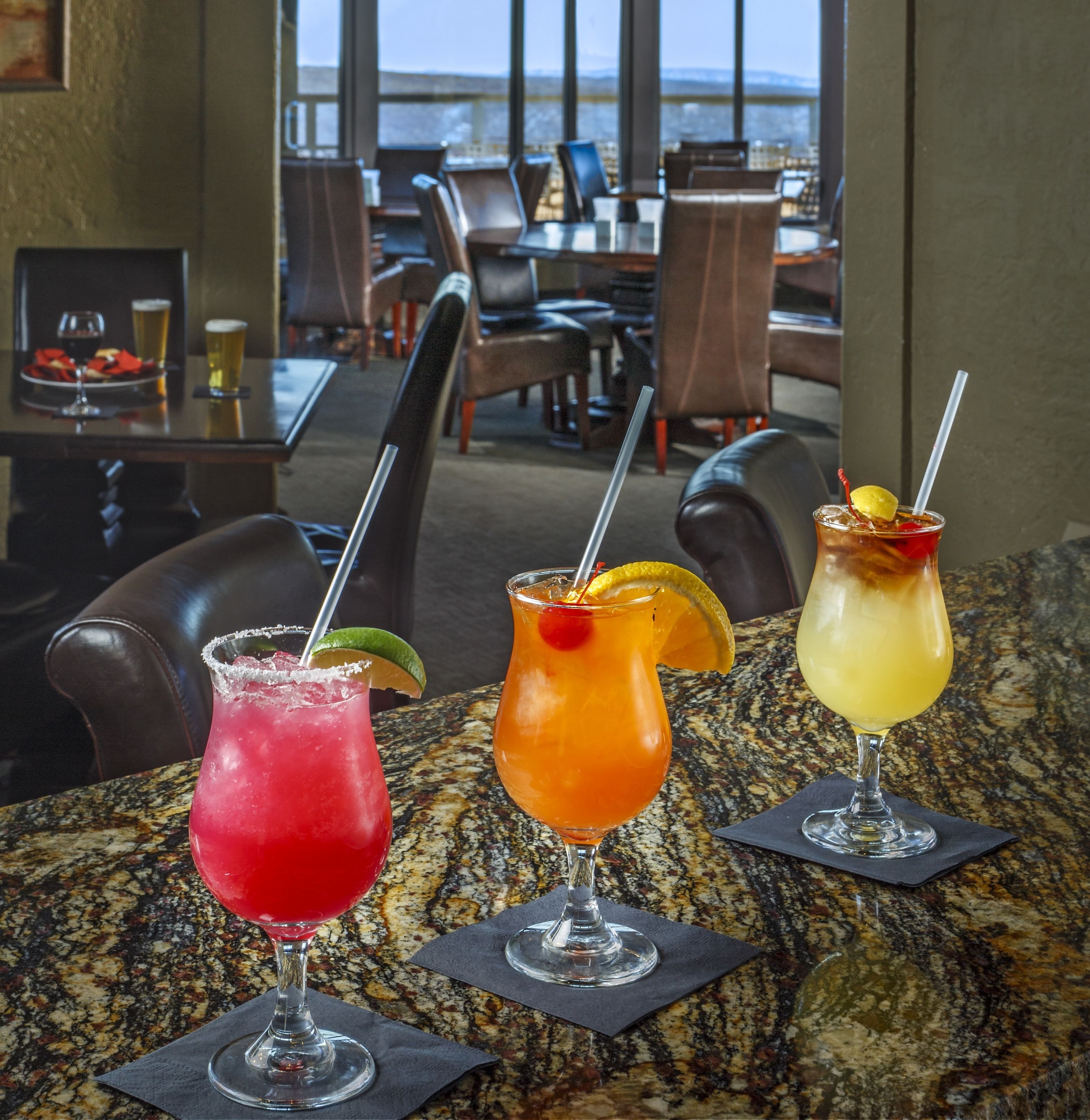 Trois cocktails sur une table, avec vue sur la ville.