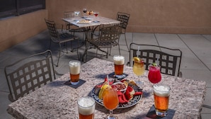 A table set for dining with drinks and a plate of food, overlooking a sunset.