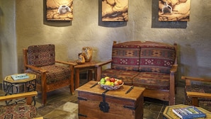A traditional room with a sofa, chairs, a wooden chest, and a small table with a book.