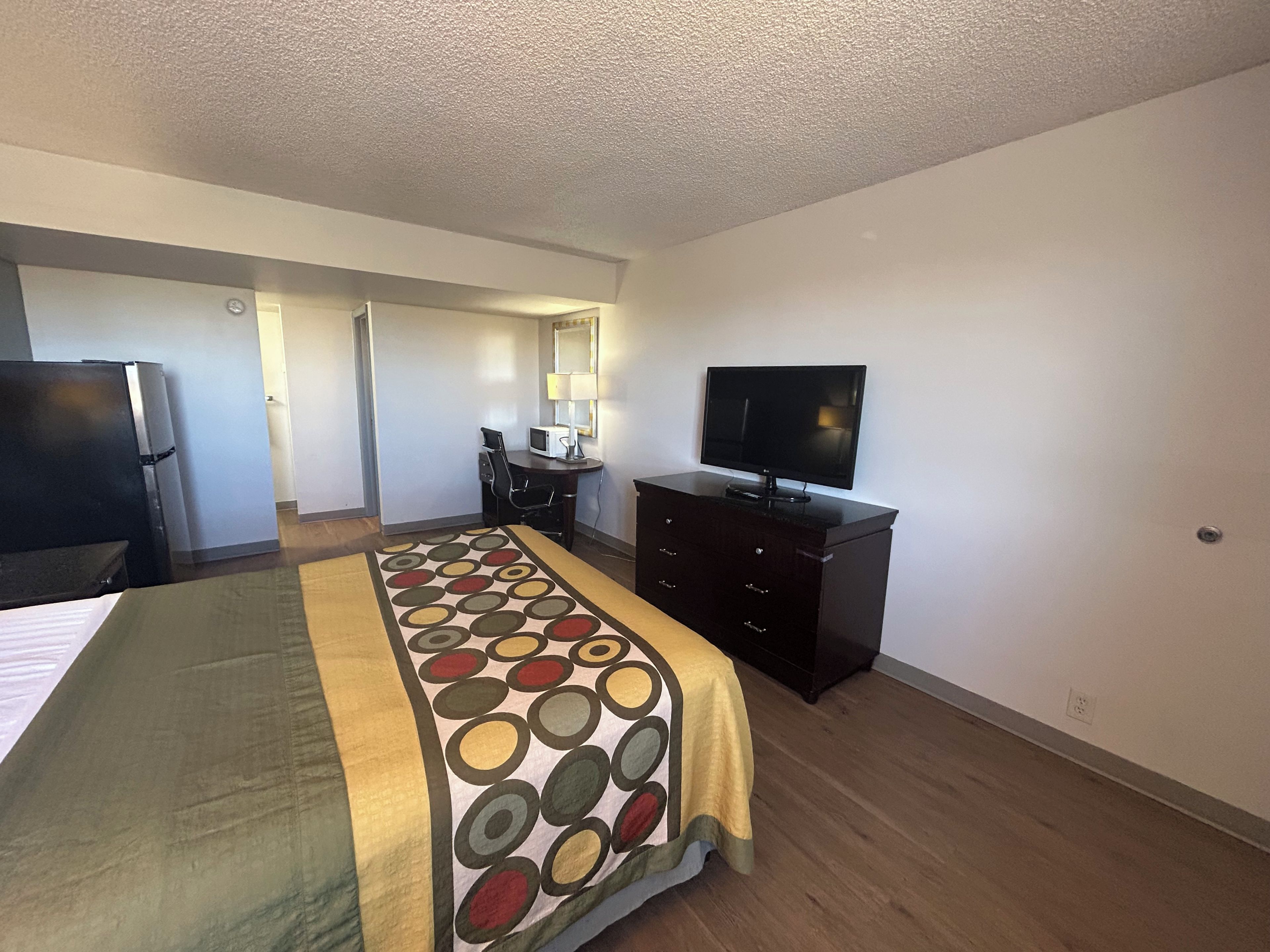 A hotel room with a bed, a desk with a computer, a television, and a microwave.