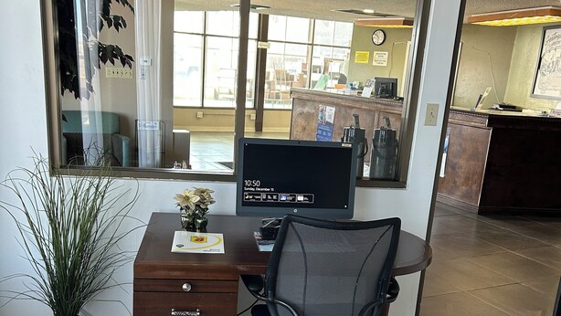 Un espacio de oficina moderno con escritorio, silla, computadora y una planta en maceta.