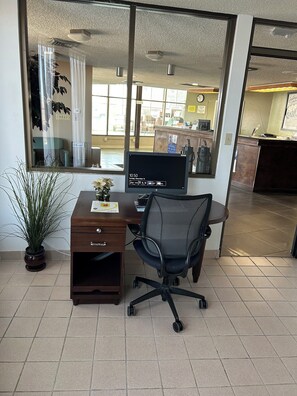 Un espacio de oficina moderno con escritorio, silla, computadora y una planta en maceta.