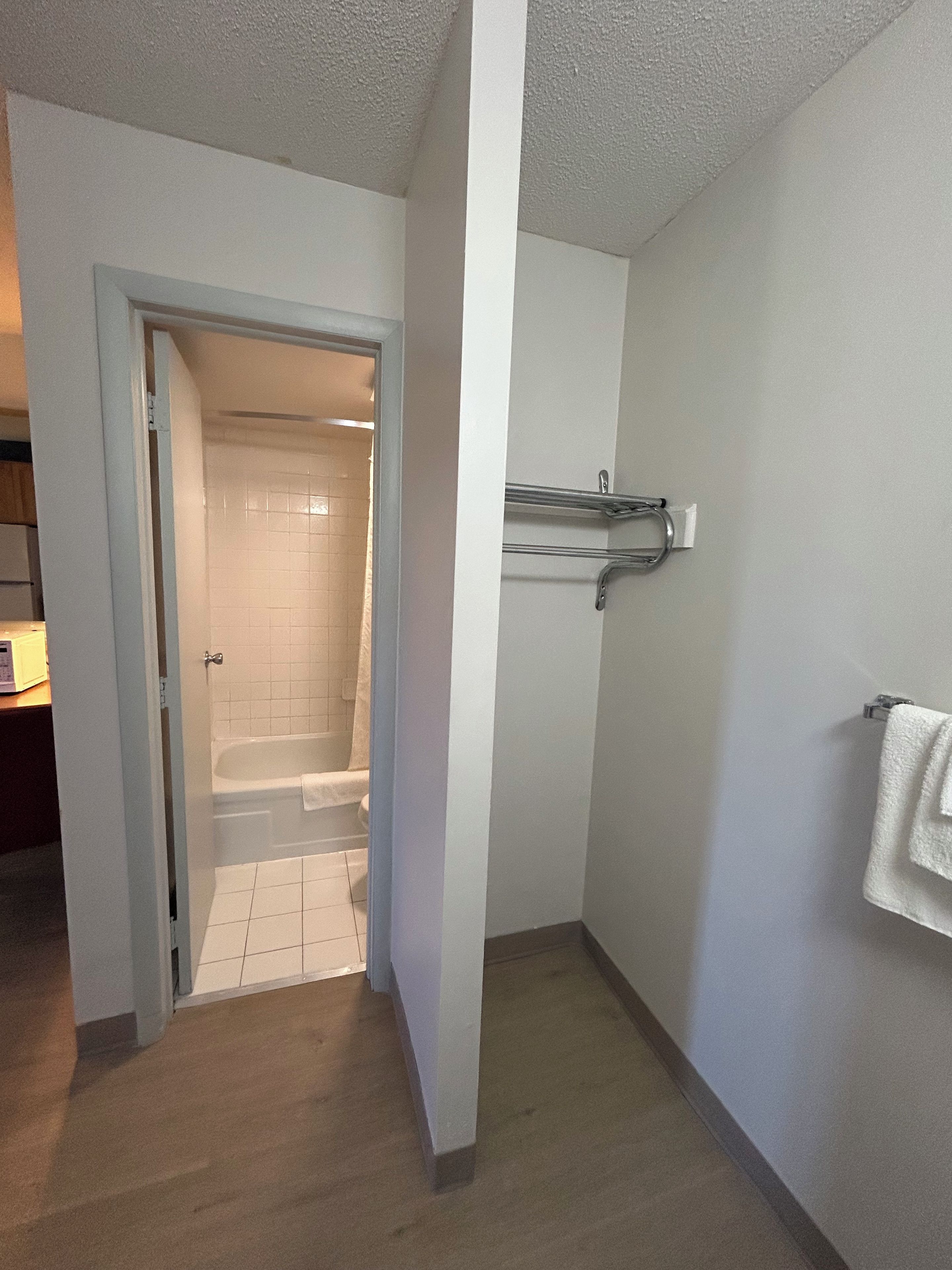 A bathroom with a shower, a towel rack, and a door leading to another room.