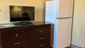 Una habitación pequeña con un aparador de madera, un televisor de pantalla plana y un refrigerador blanco.