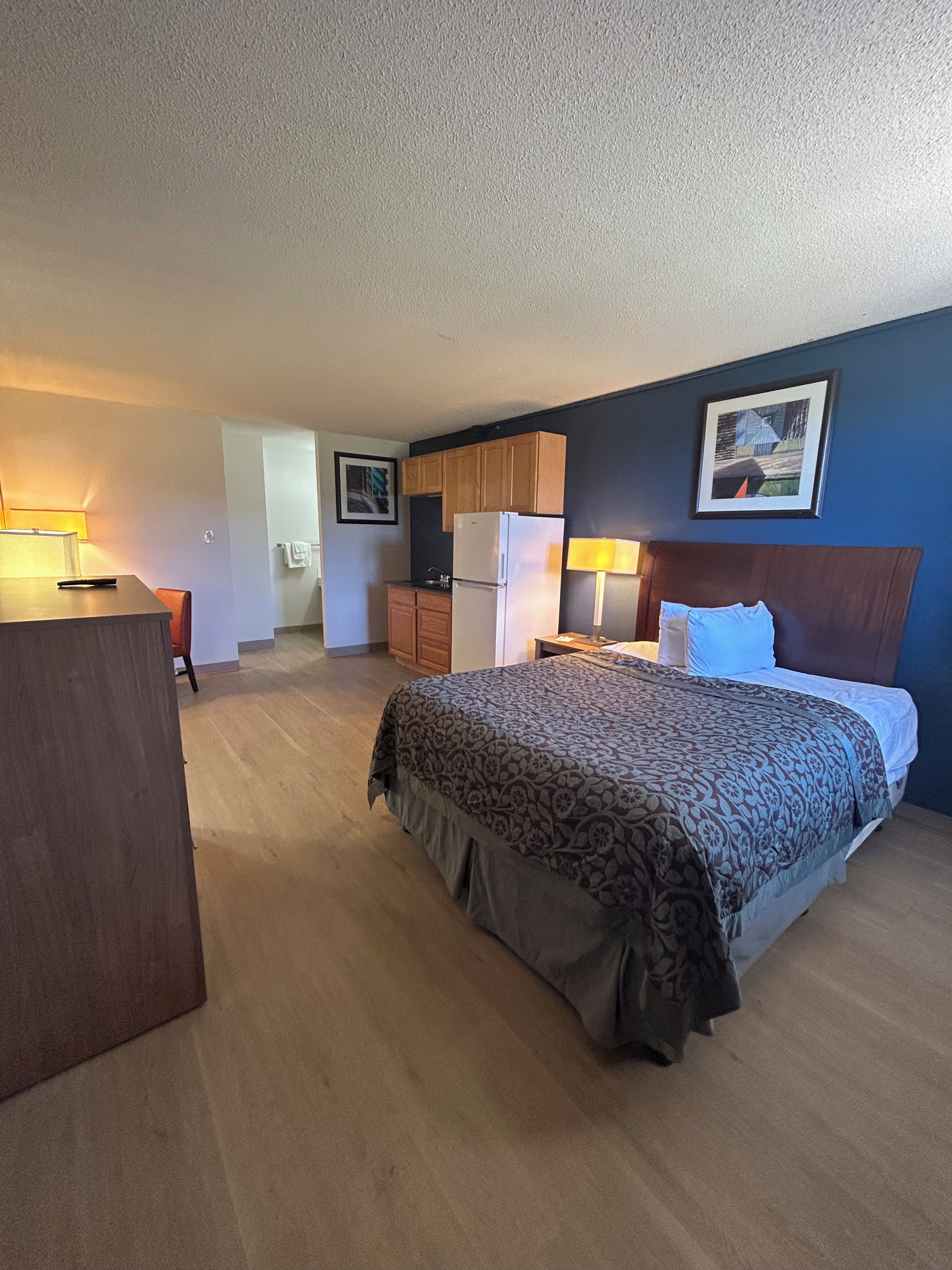 Ein Hotelzimmer mit Bett, Schreibtisch, Kühlschrank und Küchenzeile.