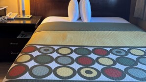 Una habitación de hotel con una cama, una mesita de noche con lámpara y un teléfono.
