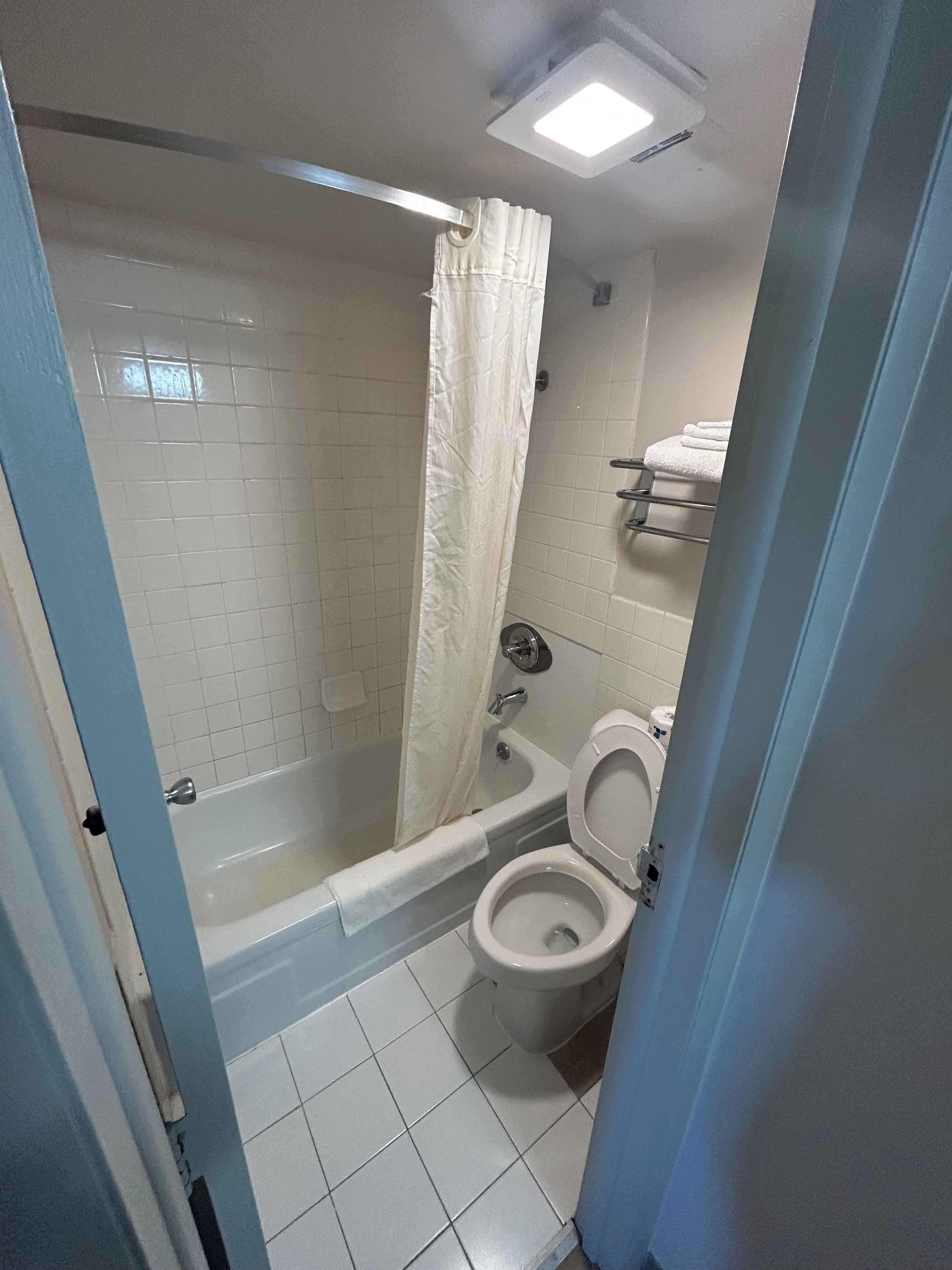 A bathroom with a bathtub, toilet, and a shower curtain.
