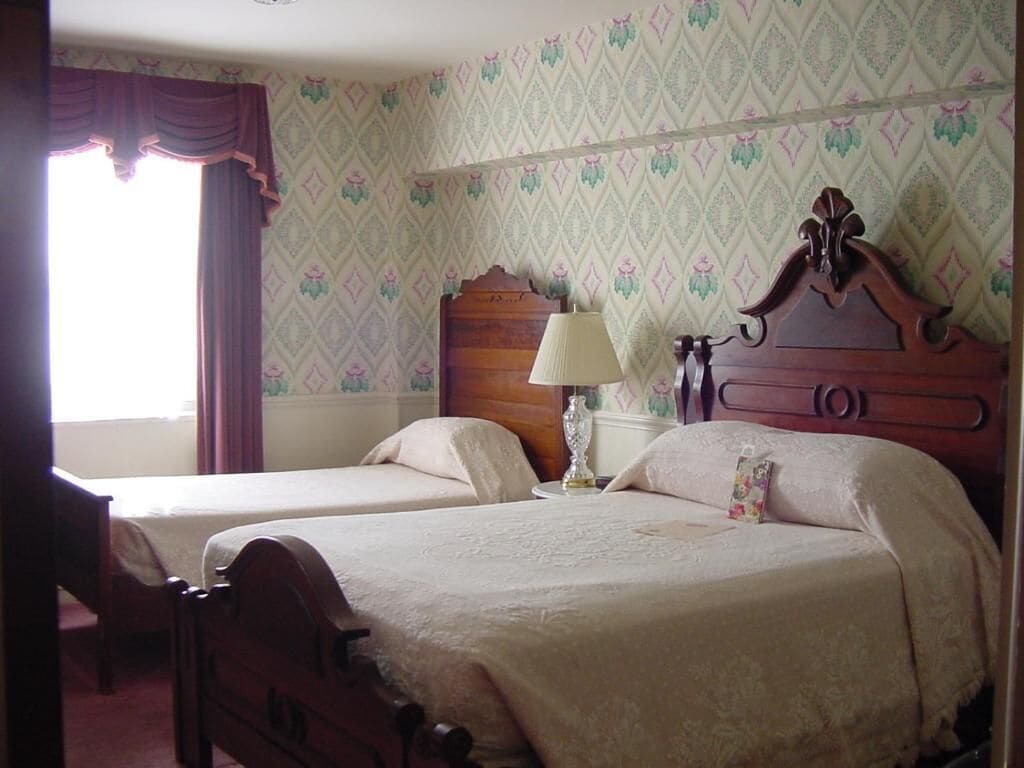 A bedroom with two single beds, a nightstand, a lamp, and a wooden headboard.