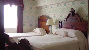 A bedroom with two single beds, a nightstand, a lamp, and a wooden headboard.