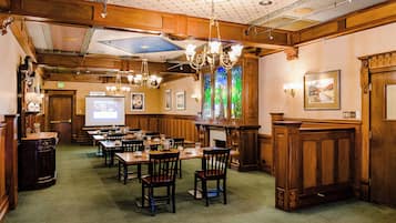 A hotel dining area with wooden paneling, chandeliers, and a projection screen.