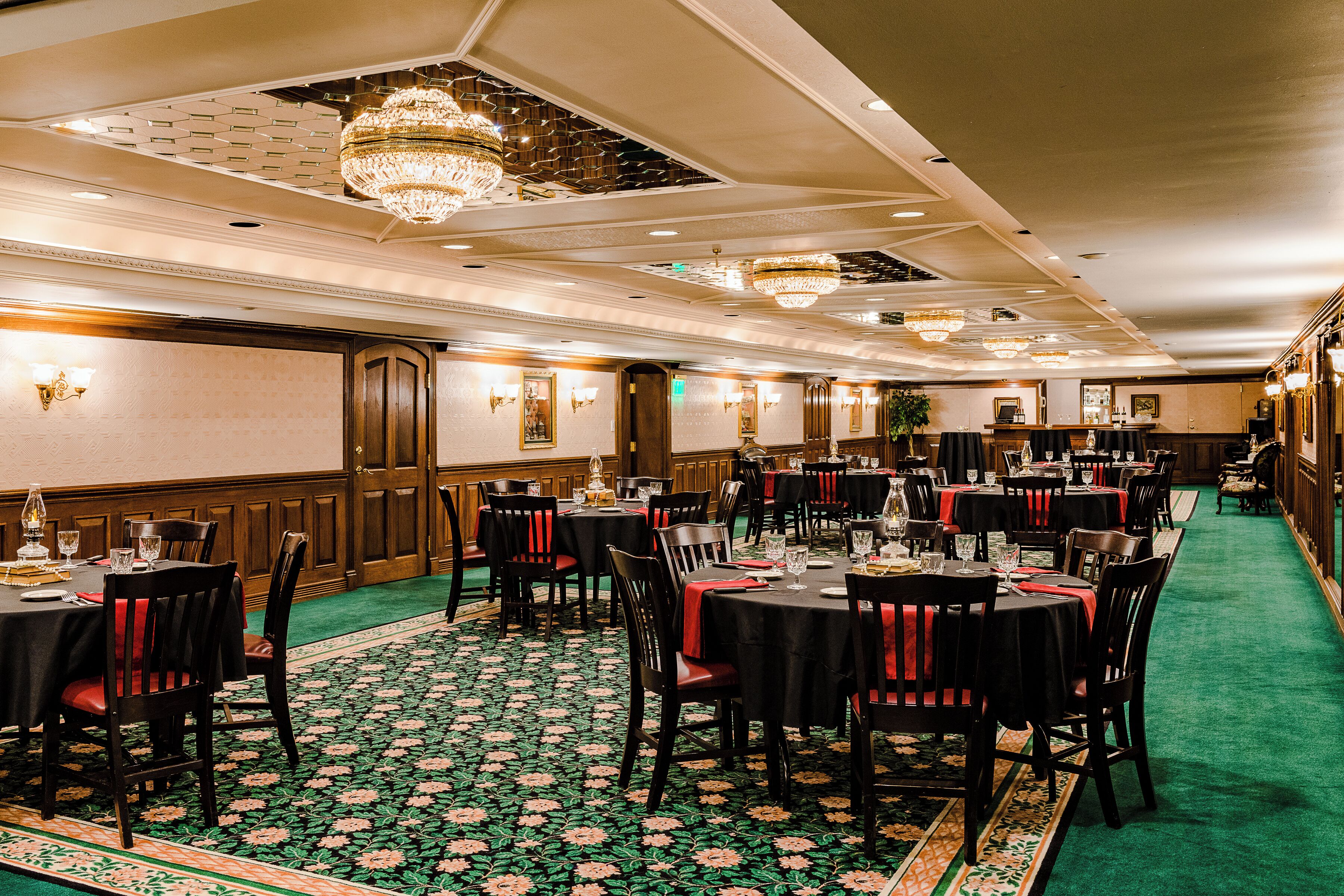 A banquet hall with multiple tables, chairs, and chandeliers.