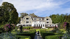 A large, two-story building with a symmetrical facade, surrounded by well-manicured gardens and hedges. - Mayflower Inn & Spa, Auberge Collection (Washington)