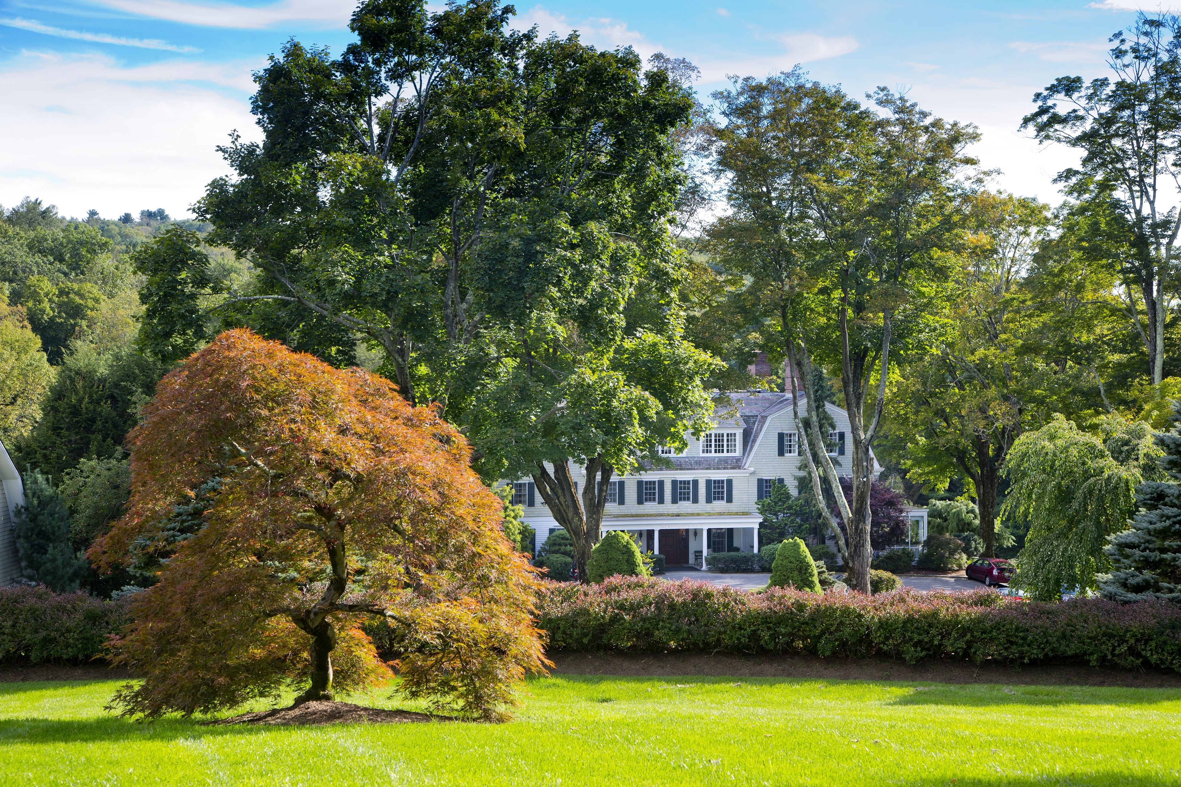 A large house surrounded by lush greenery and a well-maintained lawn.