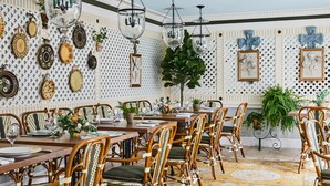 Un coin repas avec des chaises en osier, un sol à motifs et des assiettes décoratives accrochées au mur.