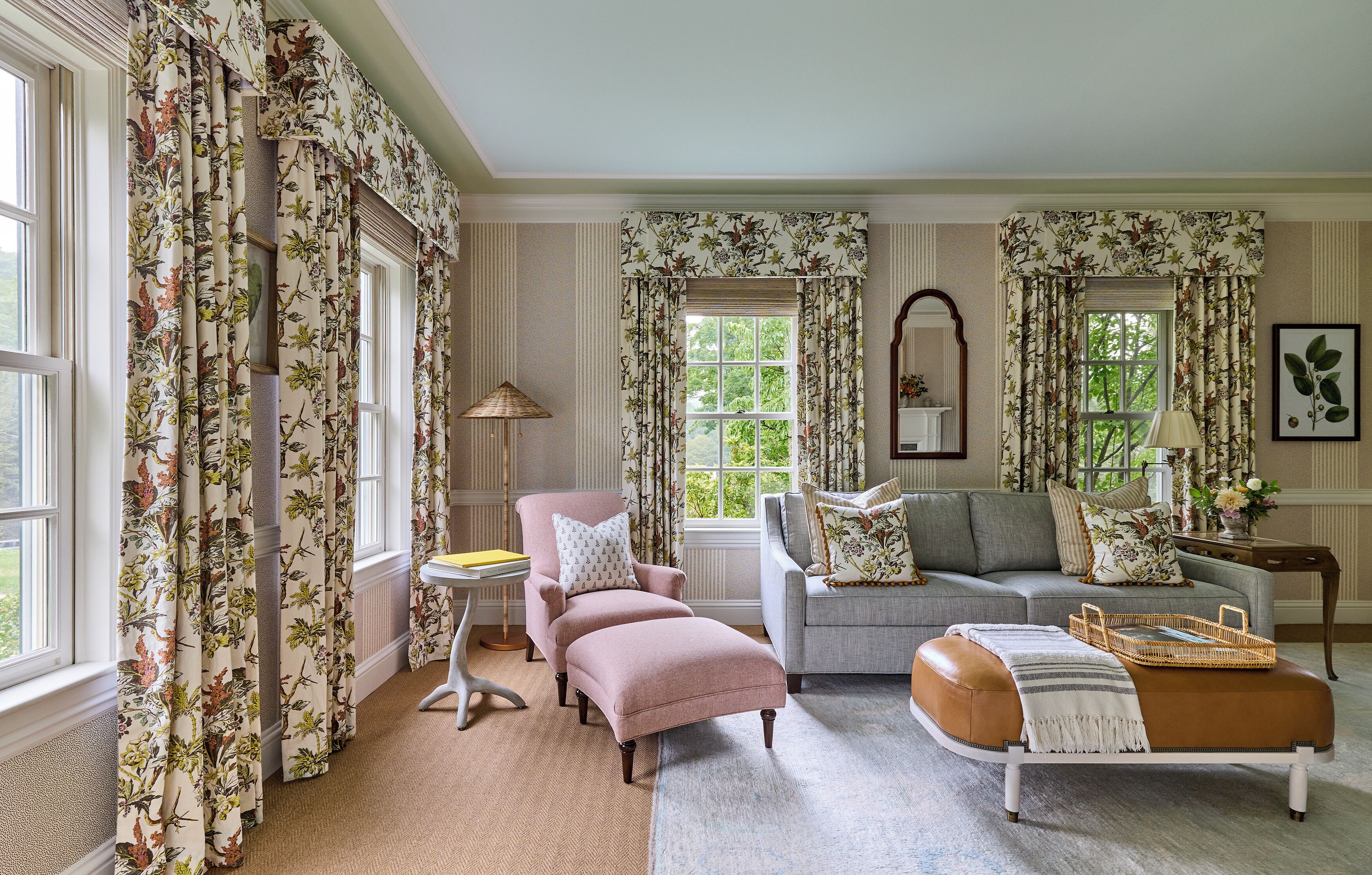 A living room with floral curtains, a sofa, a chair, and a small table.
